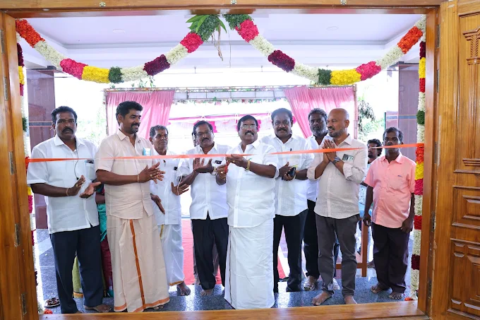 Guests at a ribbon-cutting by the flower-decorated main entrance